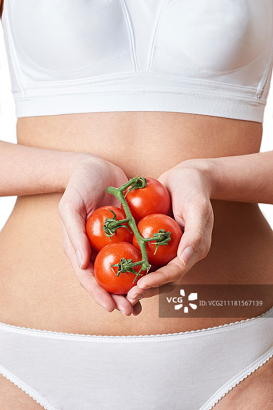 穿着内衣拿着西红柿的女人特写图片素材