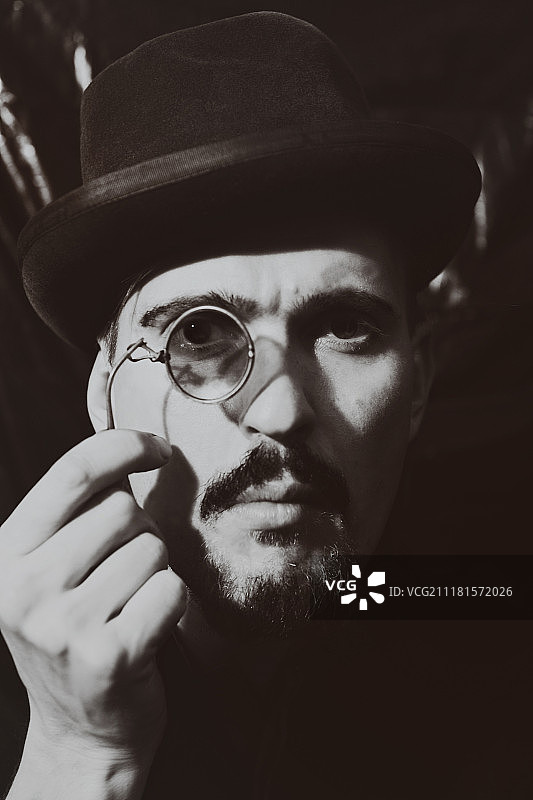 复古风格：戴帽子、持夹鼻眼镜的成熟男人图片素材