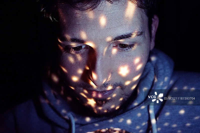 脸上投射着灯光的年轻男子图片素材