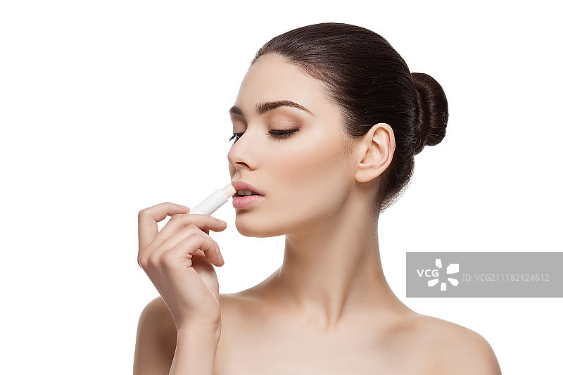 年轻女人在白色背景下涂口红图片素材