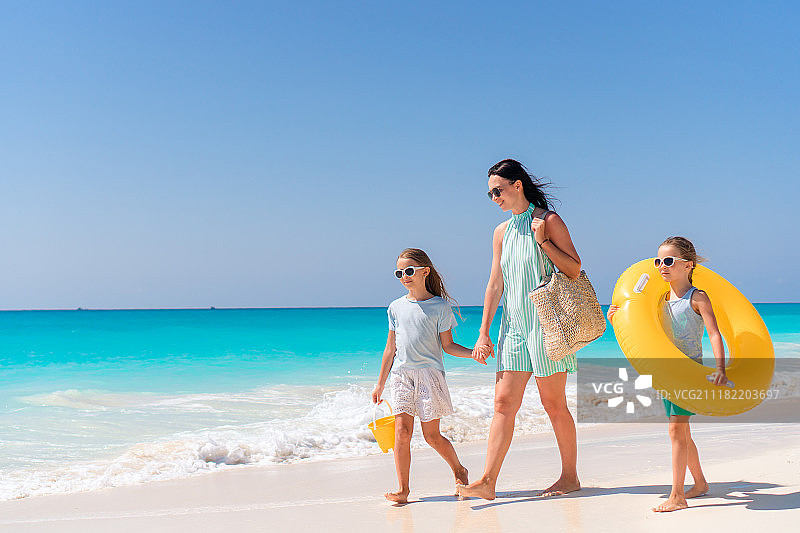 母亲带着两个小女儿在沙滩上散步图片素材