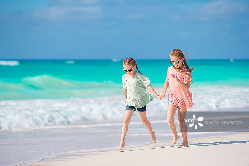 姐妹手牵手在沙滩上行走图片素材