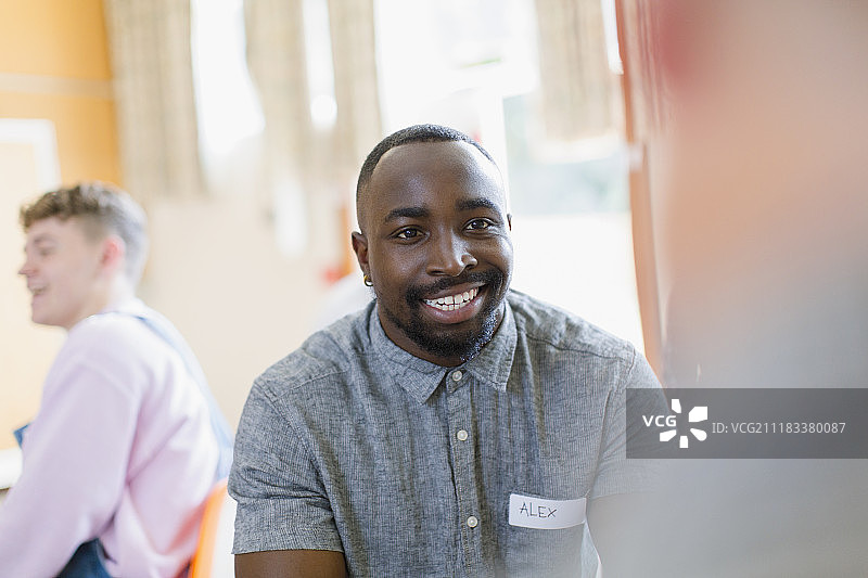 在团体治疗中倾听的微笑年轻男人图片素材