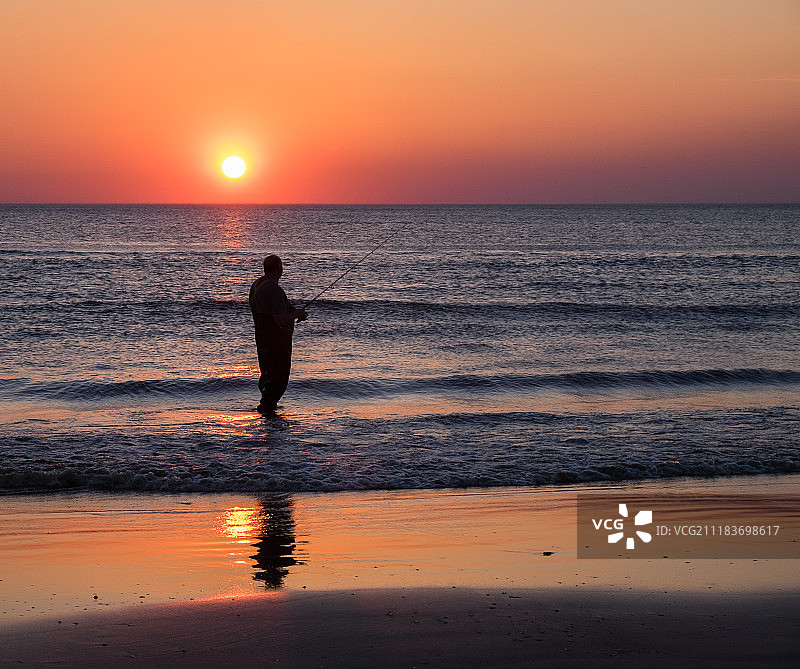 日落时分，男子在海上钓鱼图片素材