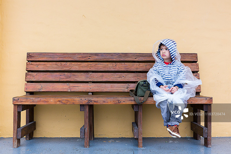 穿着雨衣坐在长凳上的孩子图片素材