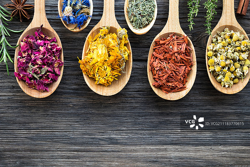 木质背景上的草本香料勺（顶部视角）图片素材