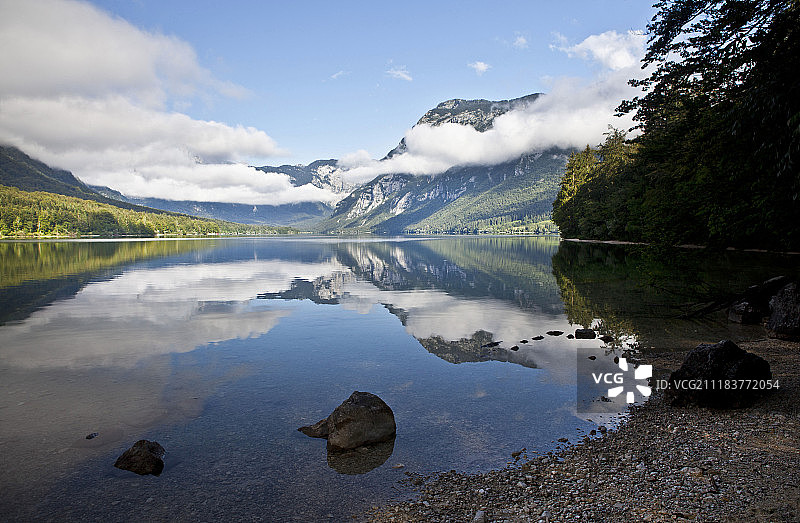 湖中倒映着云雾中的雪山图片素材