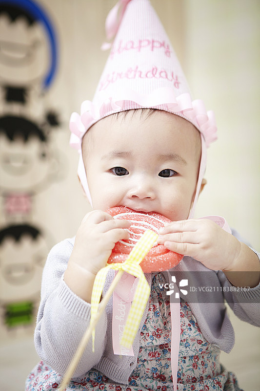 戴生日帽吃棒棒糖的婴儿摄影图片素材