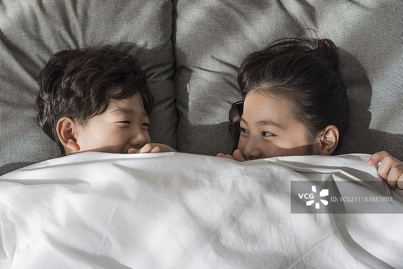 兄妹/姐弟躺在床上摄影图片素材
