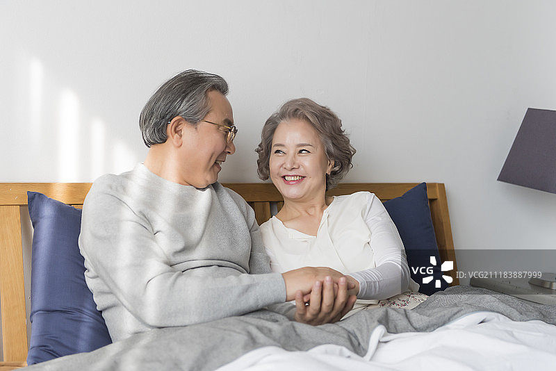 老年夫妇坐在床上手牵着手摄影图片素材