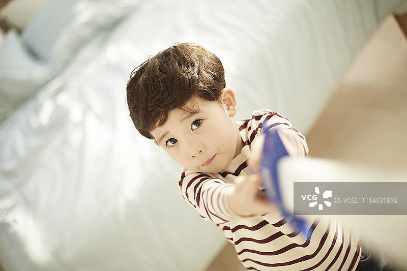 小男孩在床边玩玩具刀的照片图片素材