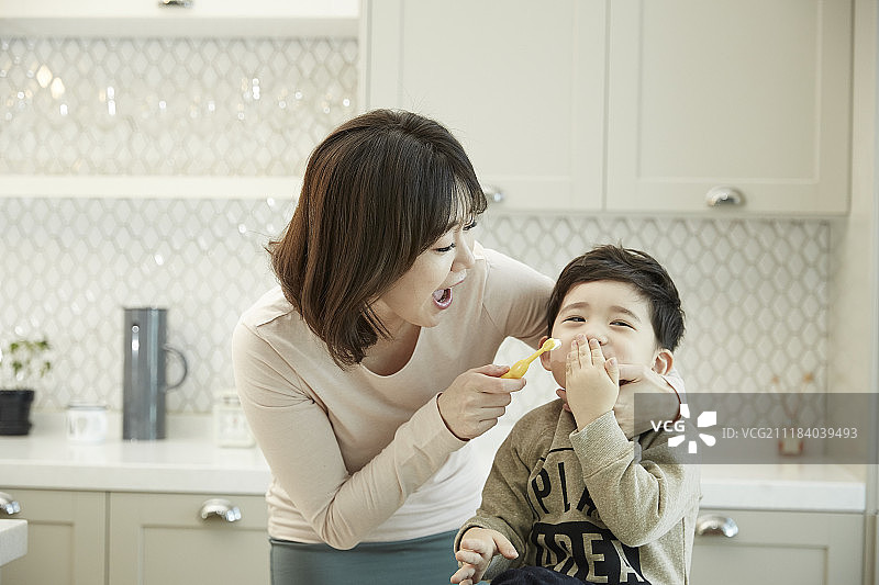 在厨房里躲避刷牙的小男孩的摄影作品图片素材