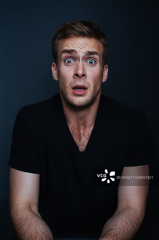 黑色背景下害怕的年轻男人图片素材