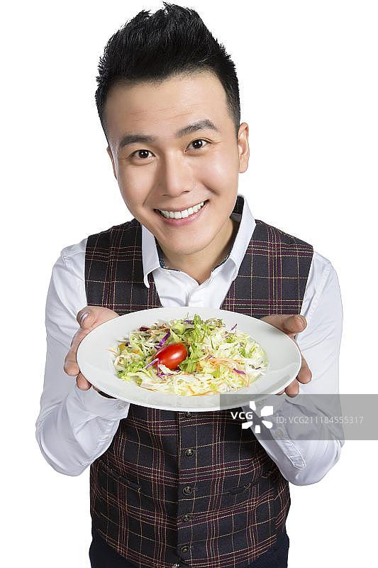 端着蔬菜沙拉的青年侍者图片素材
