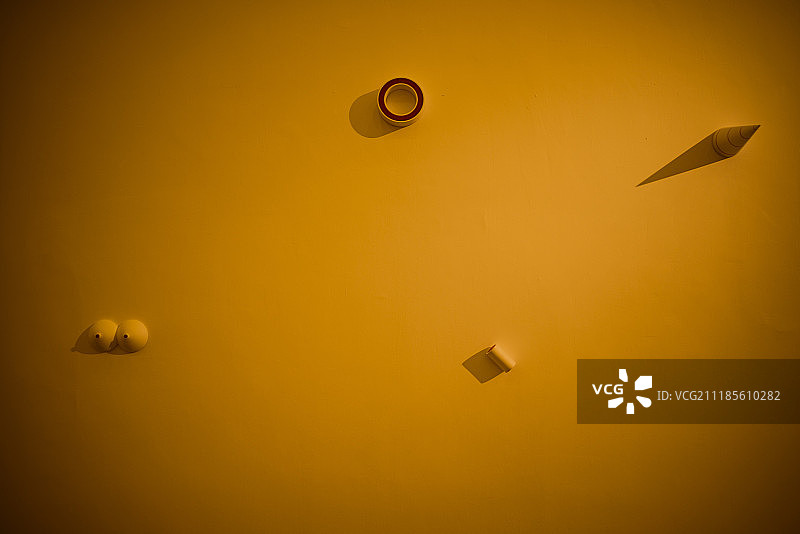 橘黄色灯光下悬挂在墙上的几何体模型图片素材