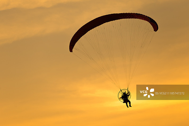 日落时分的动力滑翔伞飞行图片素材