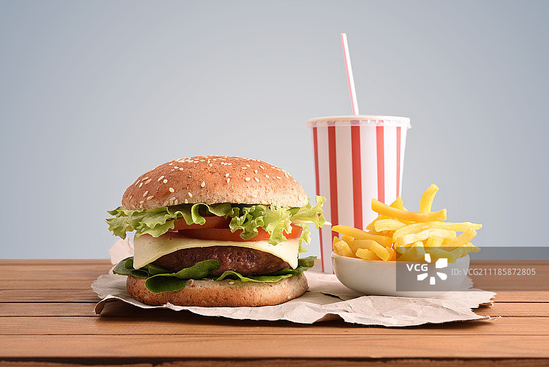 桌上的牛肉汉堡与苏打水和薯条灰色背景图片素材