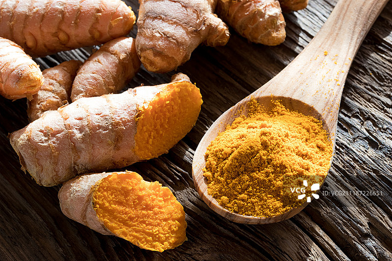 木勺上的姜黄粉和新鲜姜黄根图片素材