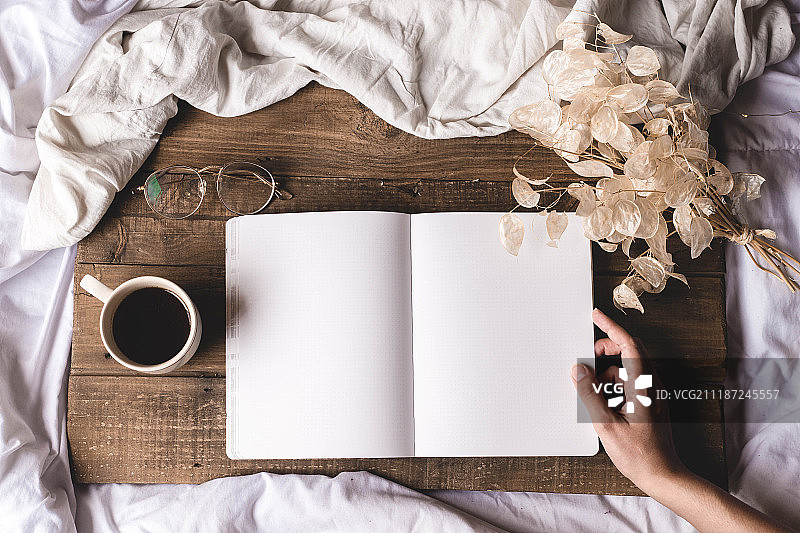 拿着笔记本坐在桌旁的女人图片素材