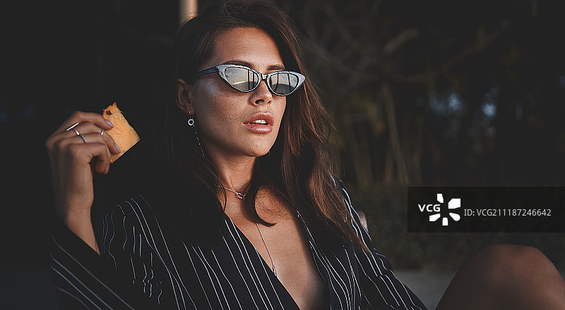 在别墅里戴着太阳镜的年轻漂亮女士的户外时尚照片，穿着时尚的女性拿着图片素材