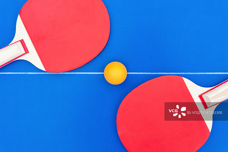 摆放于球台中线上的一对乒乓球拍和一个乒乓球图片素材