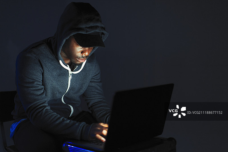 戴帽衫的少年 leaning over 笔记本电脑图片素材