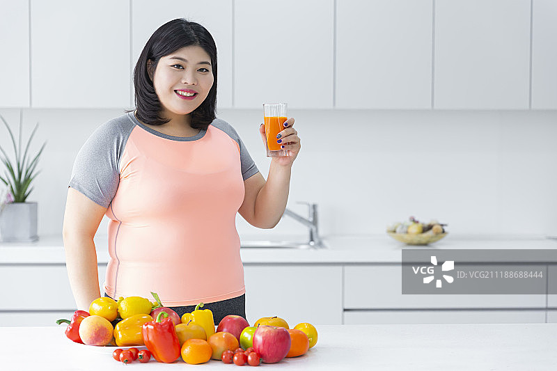 身材偏胖的女人吃健康食品和运动减肥，灰色背景图片素材