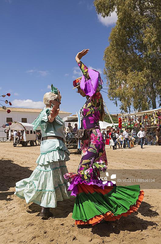 穿着色彩鲜艳的吉普赛裙子的妇女跳着塞维利亚纳舞,埃尔罗西奥五旬节朝圣,西班牙安达卢西亚韦尔瓦省,欧洲图片素材