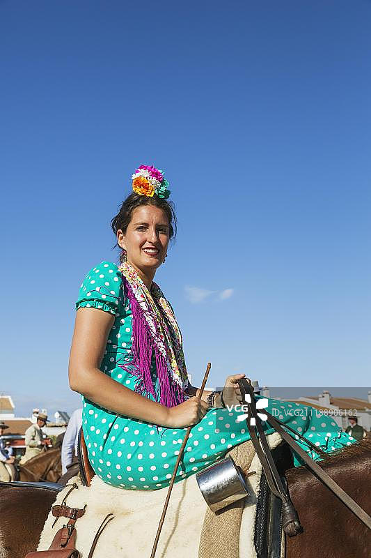 身穿吉普赛彩色连衣裙的女骑手，埃尔罗西奥五旬节朝圣，西班牙安达卢西亚图片素材