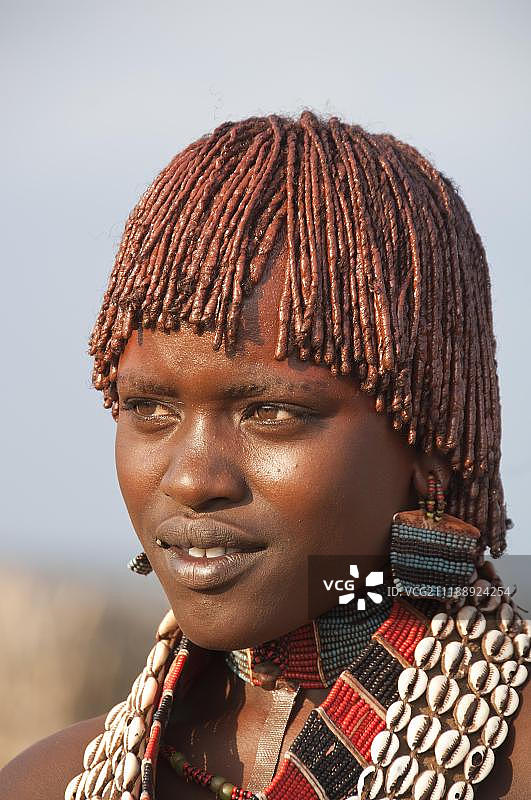年轻哈马尔族妇女的肖像，戴着用贝壳制成的项链，发型传统，头发上涂有红土，奥莫河谷，非洲埃塞俄比亚南部图片素材