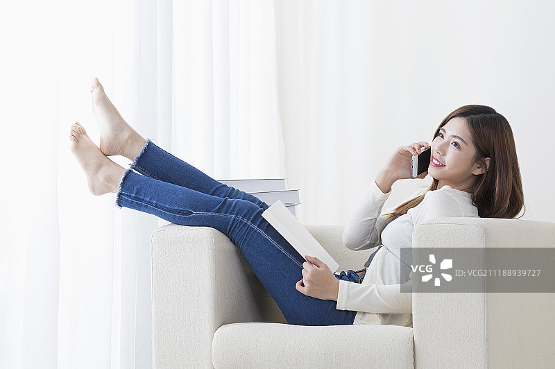 年轻女人坐在沙发上使用手机图片素材