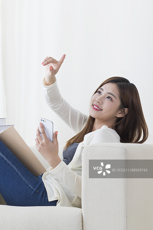 年轻女人坐在沙发上使用手机图片素材