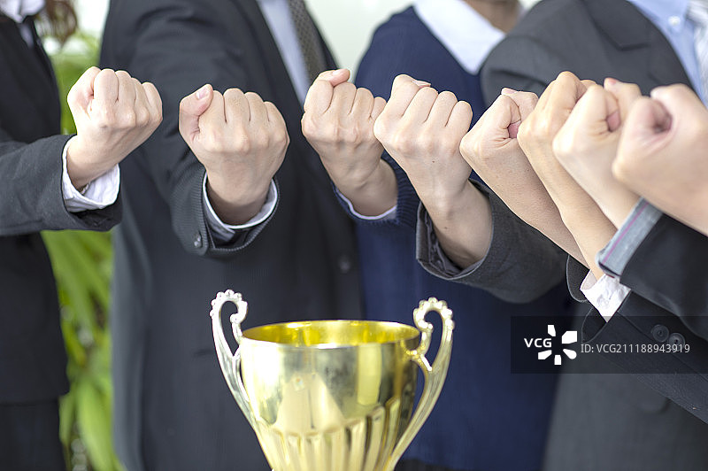 围着奖杯排一列握拳的手图片素材