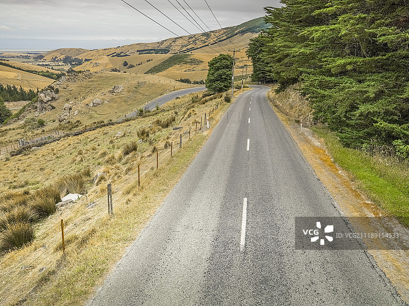 后方背景：新西兰丘陵环境中的乡村小路图片素材