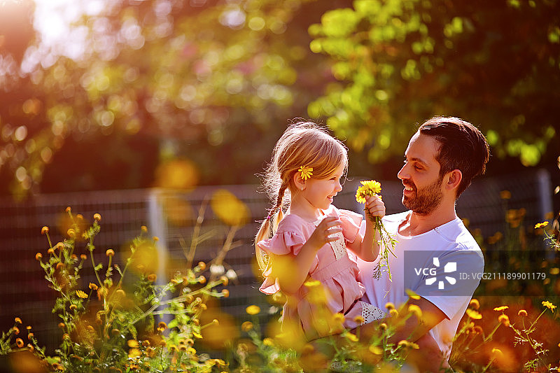 家庭时光：父亲抱着穿着粉色连衣裙的小女儿春游图片素材