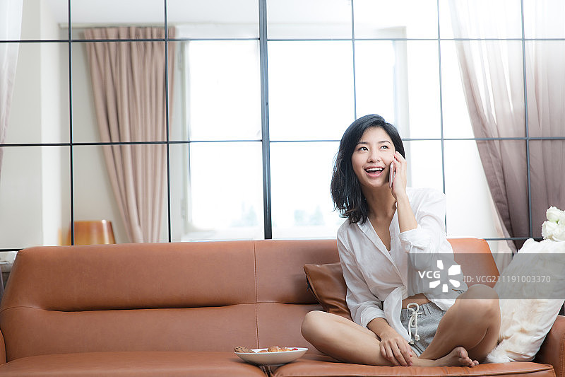 年轻女子在客厅打电话图片素材