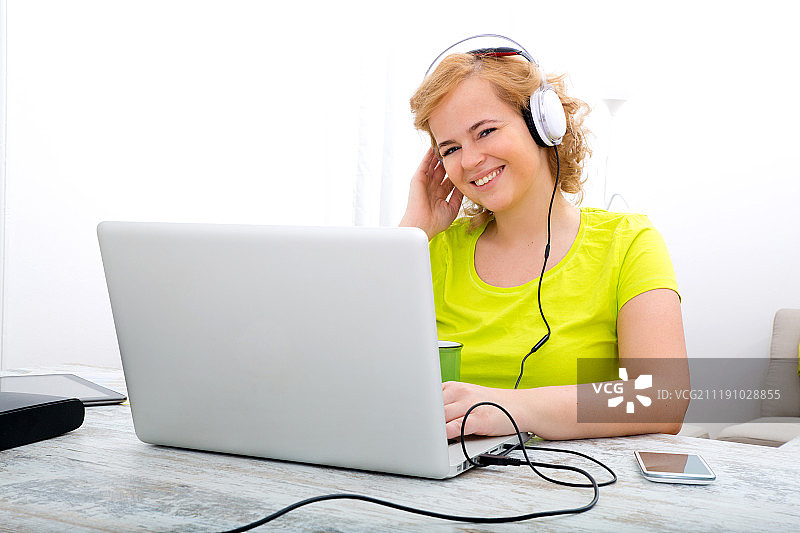 听着音频使用笔记本电脑的丰满女子图片素材