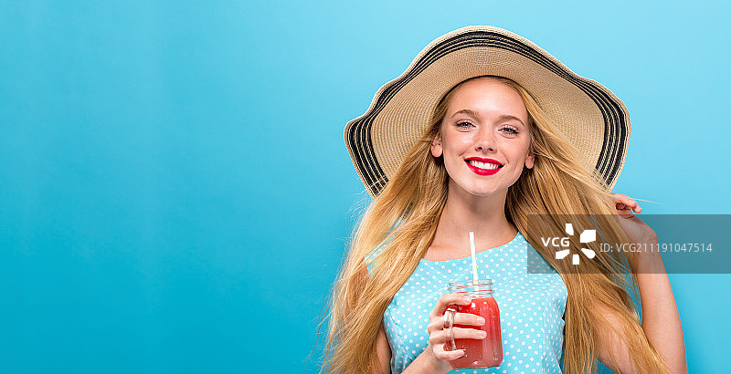快乐的年轻女人在喝冰沙。图片素材