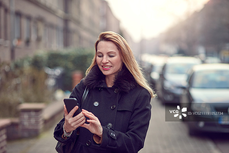 在城镇里使用手机的迷人女性图片素材