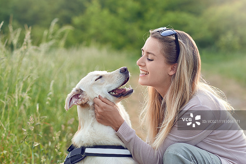 快乐的微笑的狗和它漂亮的年轻主人图片素材