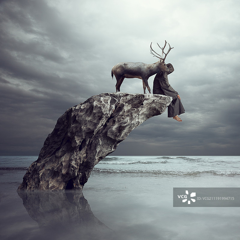 坐在海洋岩石上的人和一头鹿图片素材