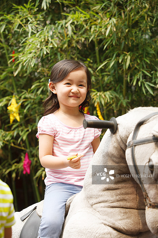 可爱的小女孩在骑摇摆木马图片素材