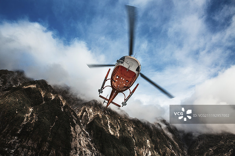飞过山峰的直升机图片素材