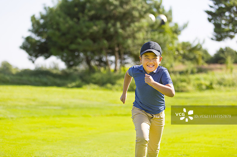 在高尔夫球场奔跑的小男孩图片素材