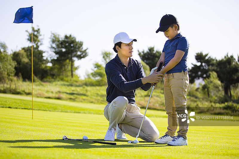 爸爸教儿子在户外打高尔夫球图片素材