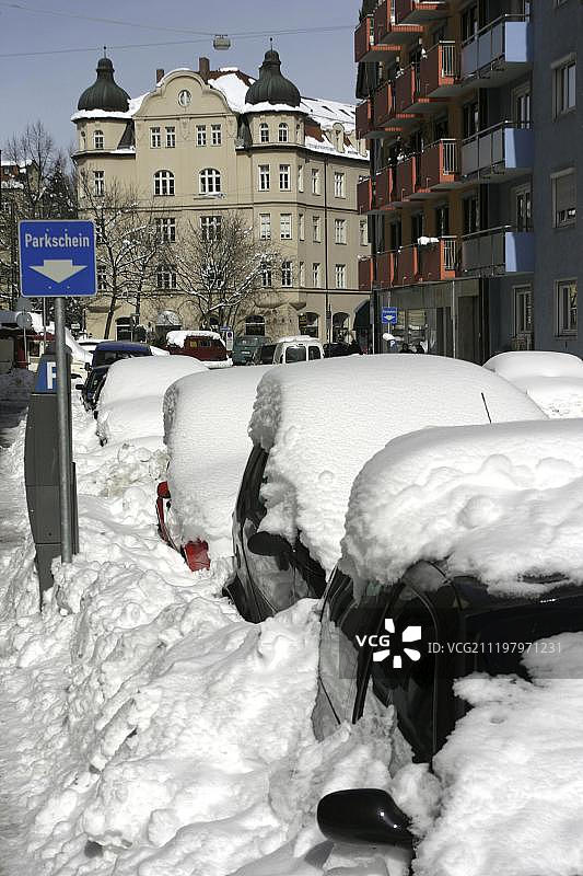 德国慕尼黑计价停车位上覆盖积雪的汽车图片素材