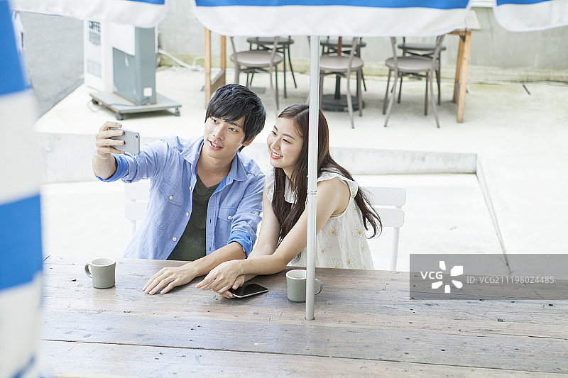 年轻夫妇在咖啡馆使用智能手机图片素材