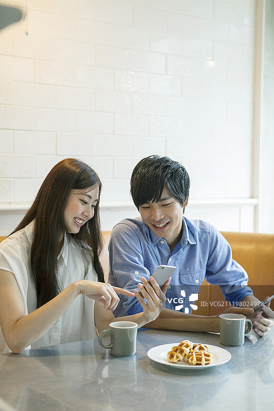 年轻夫妇在咖啡馆使用智能手机图片素材