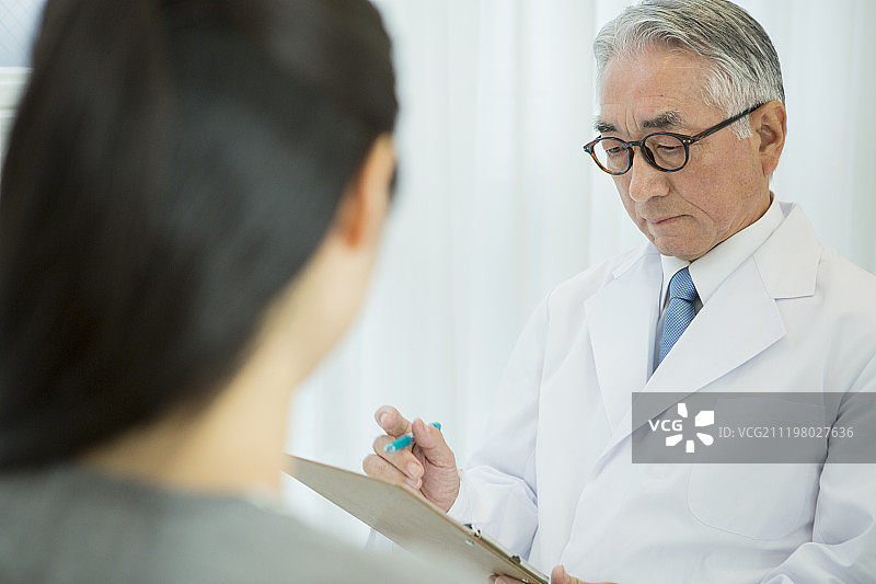 穿着白大褂的老年男医生和病人图片素材