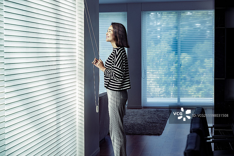 年轻女子打开窗帘图片素材